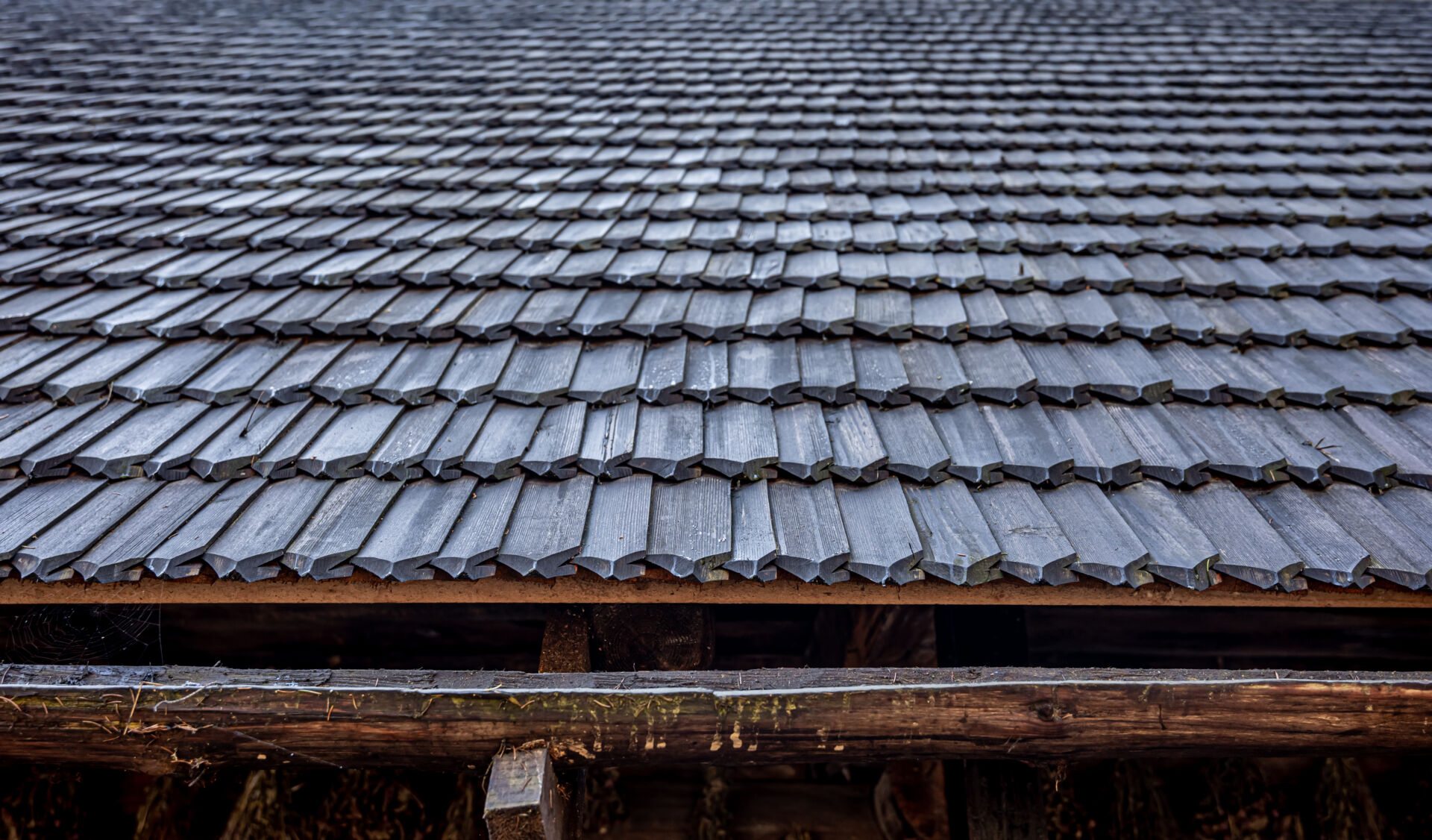 Country wood barn with a roof is made of small wooden tiles.