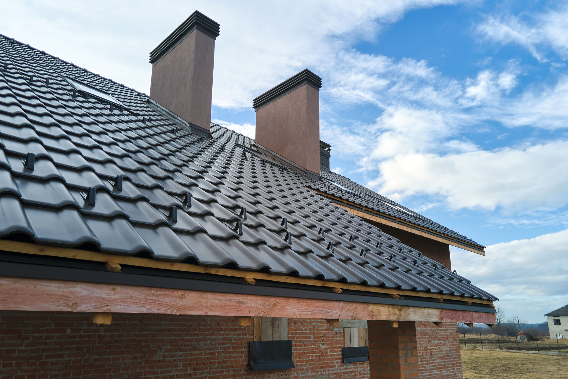Closeup snow guard for safety in winter on house roof top covered with ceramic shingles. Tiled covering of building.